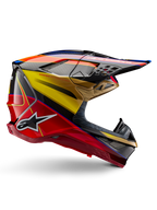 Kask Alpinestars Supertech M10 Era, kask motocrossowy, błyszczący kolor złoty, żółty i czerwony z niebieskimi i czarnymi akcentami, aerodynamiczny design ze zintegrowanym daszkiem, liczne otwory wentylacyjne zabezpieczone siatką i detale z włókna węglowego, certyfikat ECE 22.06