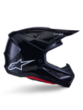 Kask Alpinestars S-M7 Solid, kask motocrossowy, czarny z połyskiem, białe logo gwiazdy i czerwone akcenty, profil boczny prezentujący aerodynamiczny design z kanciastymi otworami wentylacyjnymi i brandingiem Supertech M7 na daszku.