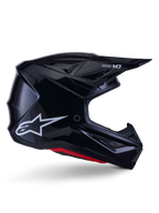 Kask Alpinestars S-M7 Solid, kask motocrossowy, czarny z połyskiem, białe logo gwiazdy i czerwone akcenty, profil boczny prezentujący aerodynamiczny design z kanciastymi otworami wentylacyjnymi i brandingiem Supertech M7 na daszku.