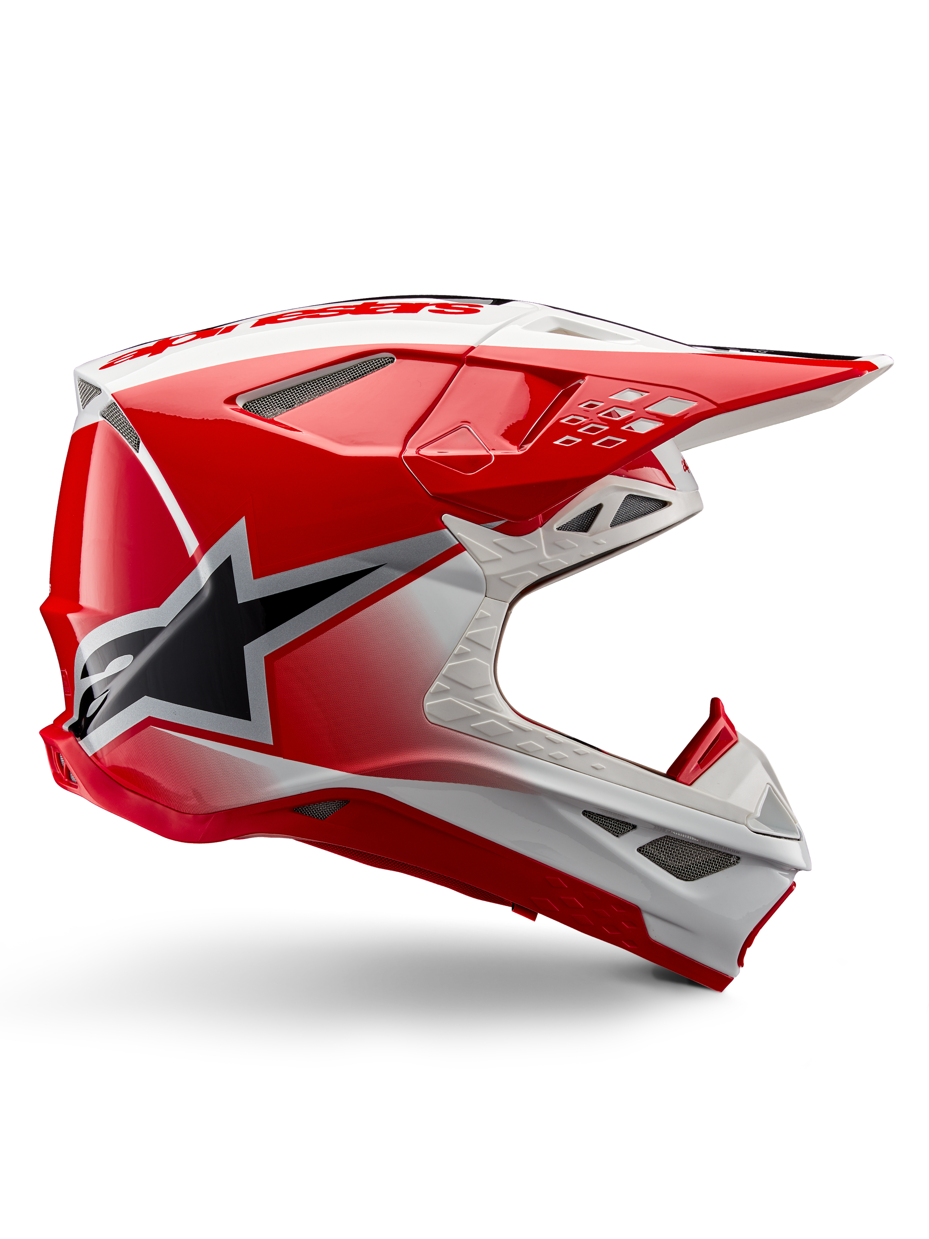 Kask Alpinestars Supertech M10 Unite, kask motocrossowy, czerwony i biały z połyskiem, widok z boku z kanciastymi wzorami geometrycznymi, czarna grafika gwiazdy, liczne siatkowe wloty powietrza i aerodynamiczny design do wyścigów off-road