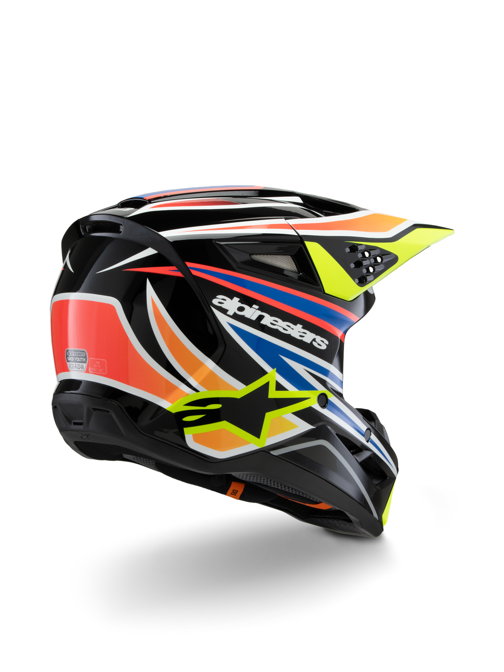 Kask Alpinestars S-M3 Youth Wurx, młodzieżowy kask motocrossowy, czarny z intensywnymi pomarańczowymi, czerwonymi, niebieskimi i jaskrawożółtymi akcentami, widok z tyłu pod kątem trzech czwartych ukazujący aerodynamiczną skorupę i otwory wentylacyjne, błyszczące wykończenie z wyraźnym brandingiem Alpinestars