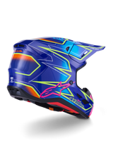 Kask Alpinestars S-M7 Cast, kask motocrossowy, błyszczący niebieski, różowy i żółty fluo, widok z tyłu pod kątem trzech czwartych ukazujący aerodynamiczną skorupę z wyrazistymi kanciastymi grafikami, różowe logo Astar i zintegrowane otwory wentylacyjne do wyścigów off-road