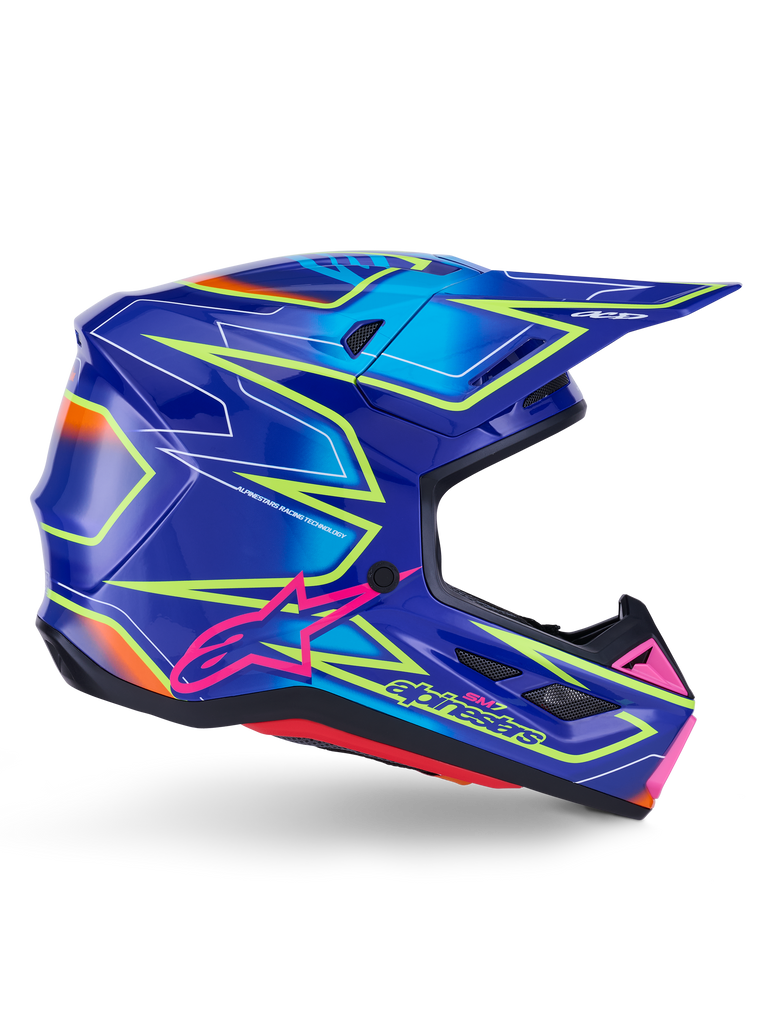 Kask Alpinestars S-M7 Cast, kask motocrossowy, niebieski, różowy i żółty fluo z połyskiem, widok z boku prezentujący wyraziste wzory geometryczne, różowe logo Alpinestars oraz wentylowaną aerodynamiczną skorupę.