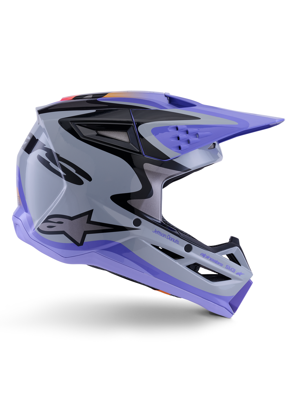 Alpinestars S-M3 Jettson Helmet ECE 22.06, kask motocrossowy, szaro-fioletowo-czarny błyszczący, widok z boku prezentujący fioletowy daszek i osłonę szczęki, smukła aerodynamiczna skorupa z czarną grafiką, liczne otwory wentylacyjne i logo „Jettson Donuts” z boku