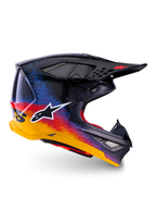 Alpinestars Limited Edition Supertech M10 Black Hole, kask motocrossowy, czarna skorupa z czerwonym, niebieskim i żółtym gradientowym wzorem typu splatter, białe logo gwiazdy z boku, aerodynamiczny profil z otworami wentylacyjnymi osłoniętymi siatką, czerwona wyściółka i długi czarny daszek.
