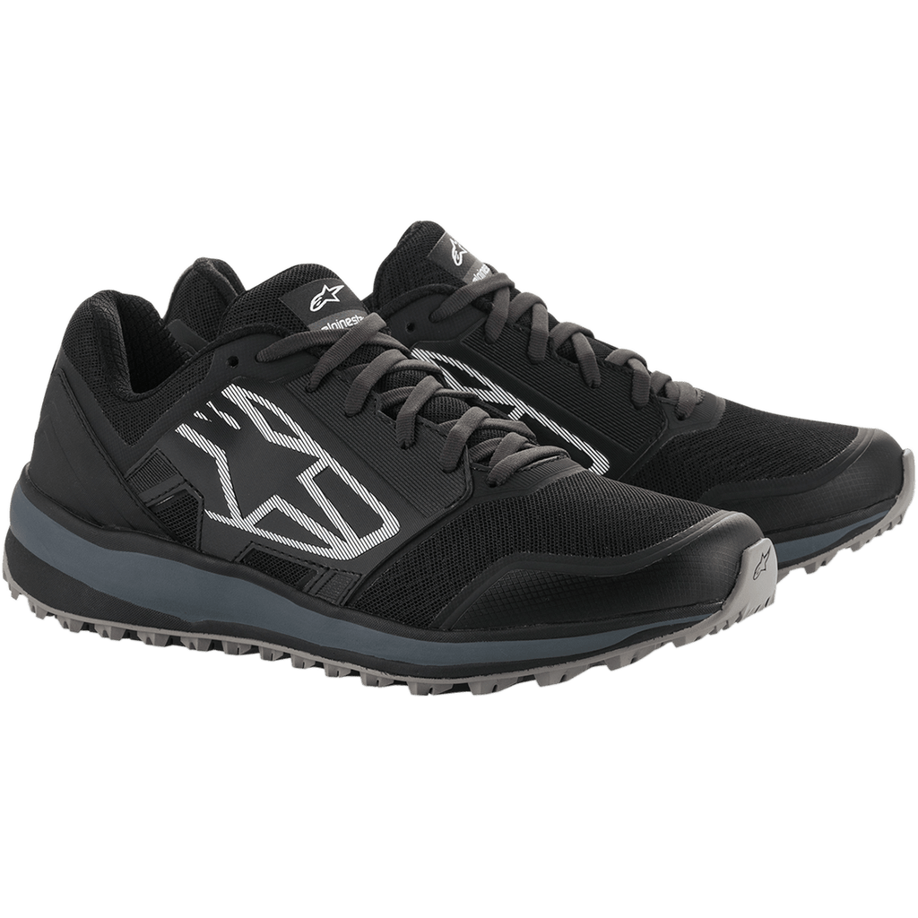 Buty Alpinestars Meta Trail, wyczynowe buty do biegania, czarne i ciemnoszare, duże białe prążkowane logo Astars z boku, sznurowana konstrukcja z wytrzymałą szarą podeszwą, zaprojektowane dla całodniowego komfortu w padoku