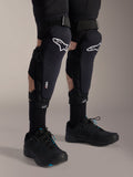 Ochraniacze kolan Alpinestars A-Impact Plasma Pro, czarno-białe, z brandingiem technologii Nucleon PLASMA, noszone z czarnymi skarpetami i czarnymi butami do rowerów górskich, bezpieczne paski na rzepy, ergonomiczny sprzęt ochronny do kolarstwa terenowego