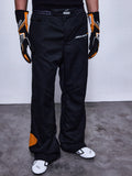 Alpinestars RSRV Arena Suit Pants, czarne spodnie wyścigowe z logo McLaren i Alpinestars, pomarańczowe wstawki na boku, osoba w czarno-pomarańczowych rękawicach i białych butach wyścigowych