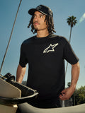 Alpinestars One Oversized CSF Tee, koszulka z krótkim rękawem, czarna z białym logo Astars, noszona przez mężczyznę w czarnej czapce typu trucker, plenerowa sceneria z palmami i motocyklem, casualowy streetwear motorsportowy