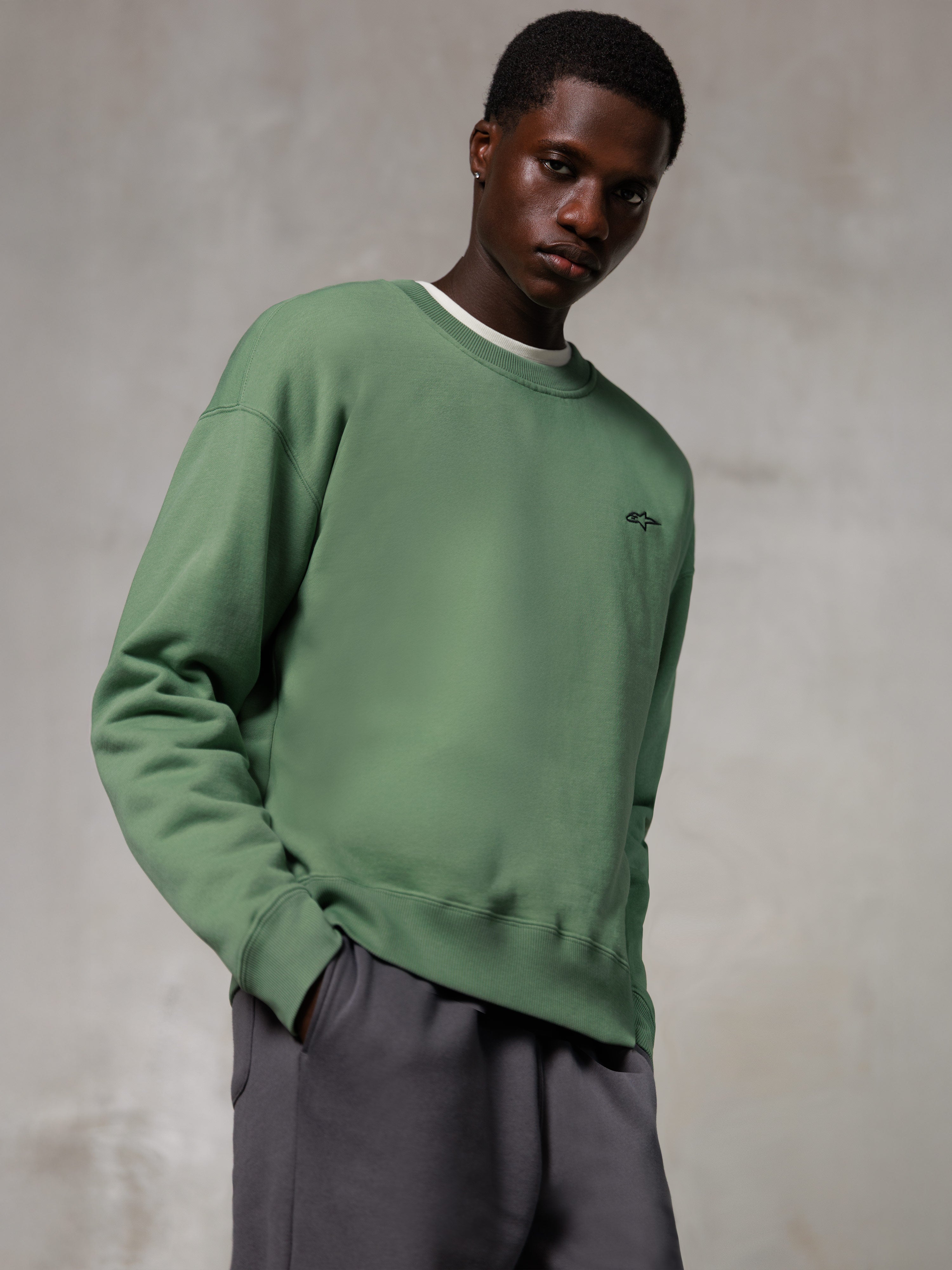 Alpinestars Essentials Ageless Crew, Crewneck Sweatshirt, Cactus Green, featuring a small black Alpinestars logo on the chest, worn by a model with grey pants, casual lifestyle streetwear