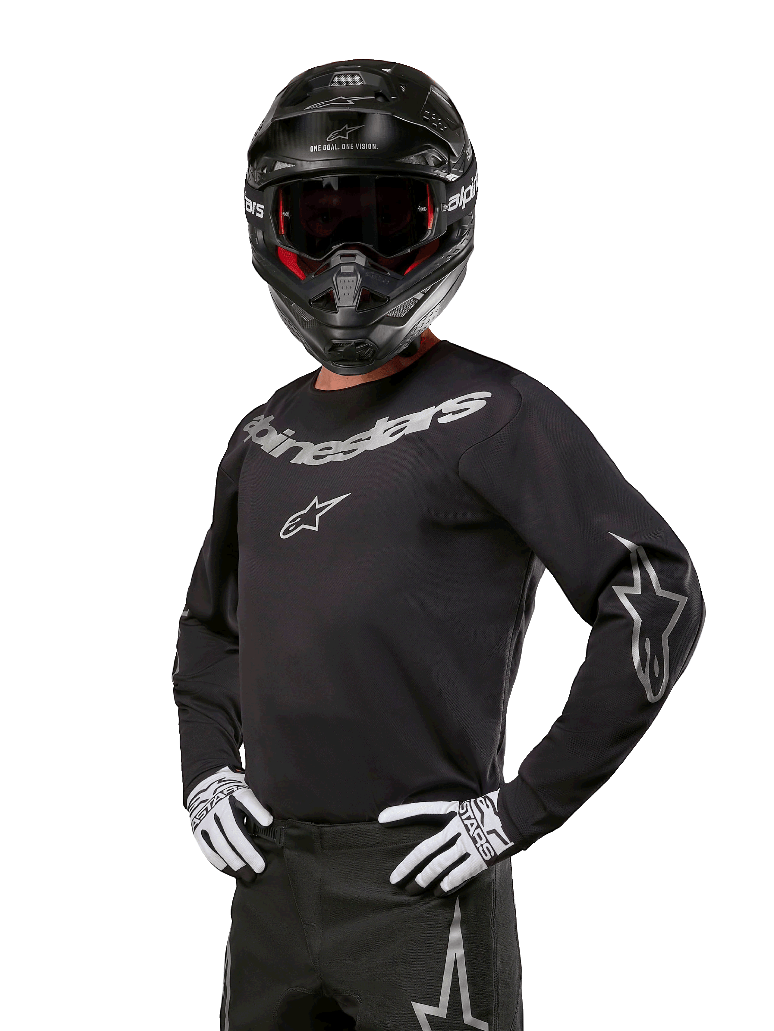 Zestaw Alpinestars 2024 Fluid Graphite, zawodnik motocrossowy w czarno-szarej koszulce z wyraźnymi szarymi logotypami, pasujące spodnie, czarny kask i biało-czarne rękawice, sportowy krój do wyścigów motocrossowych off-road