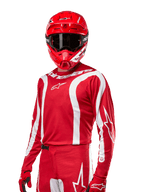 Alpinestars 2024 Fluid Lurv Jersey, koszulka motocrossowa, czerwono-biała, noszona z dopasowanym czerwonym kaskiem i rękawicami, sportowy design z białymi zakrzywionymi pasami i logo Alpinestars