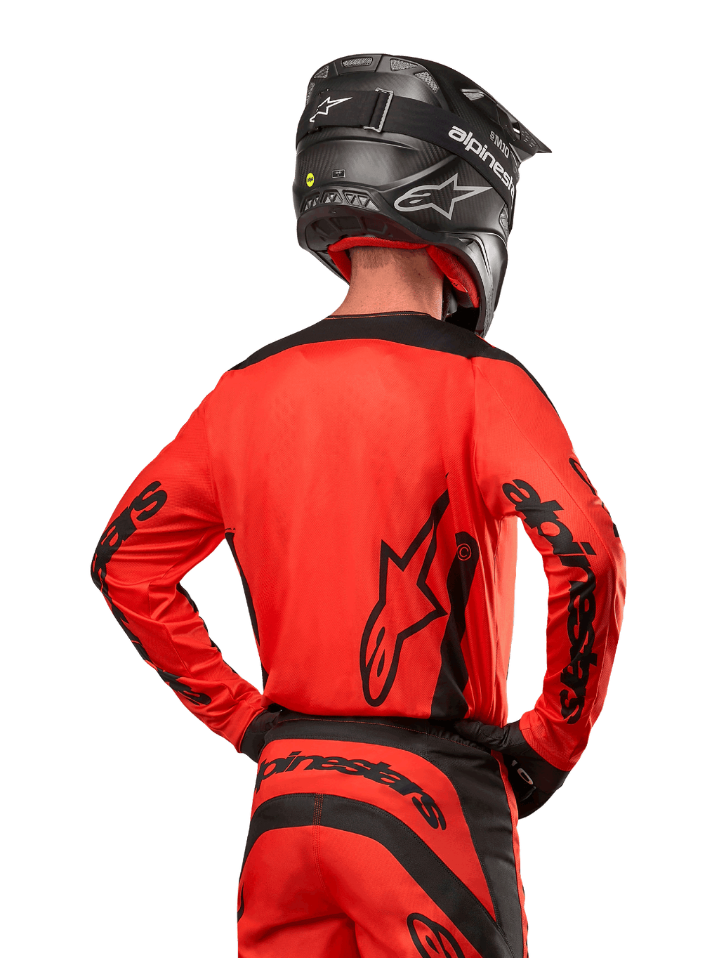 Motocyklista motocrossowy widoczny od tyłu w koszulce Alpinestars 2024 Fluid Lurv w kolorze jaskrawopomarańczowym i czarnym, z wyraźnym brandingiem Alpinestars na plecach i rękawach, w zestawie z dopasowanymi spodniami motocrossowymi i czarnym kaskiem, zaprojektowana do jazdy off-road.