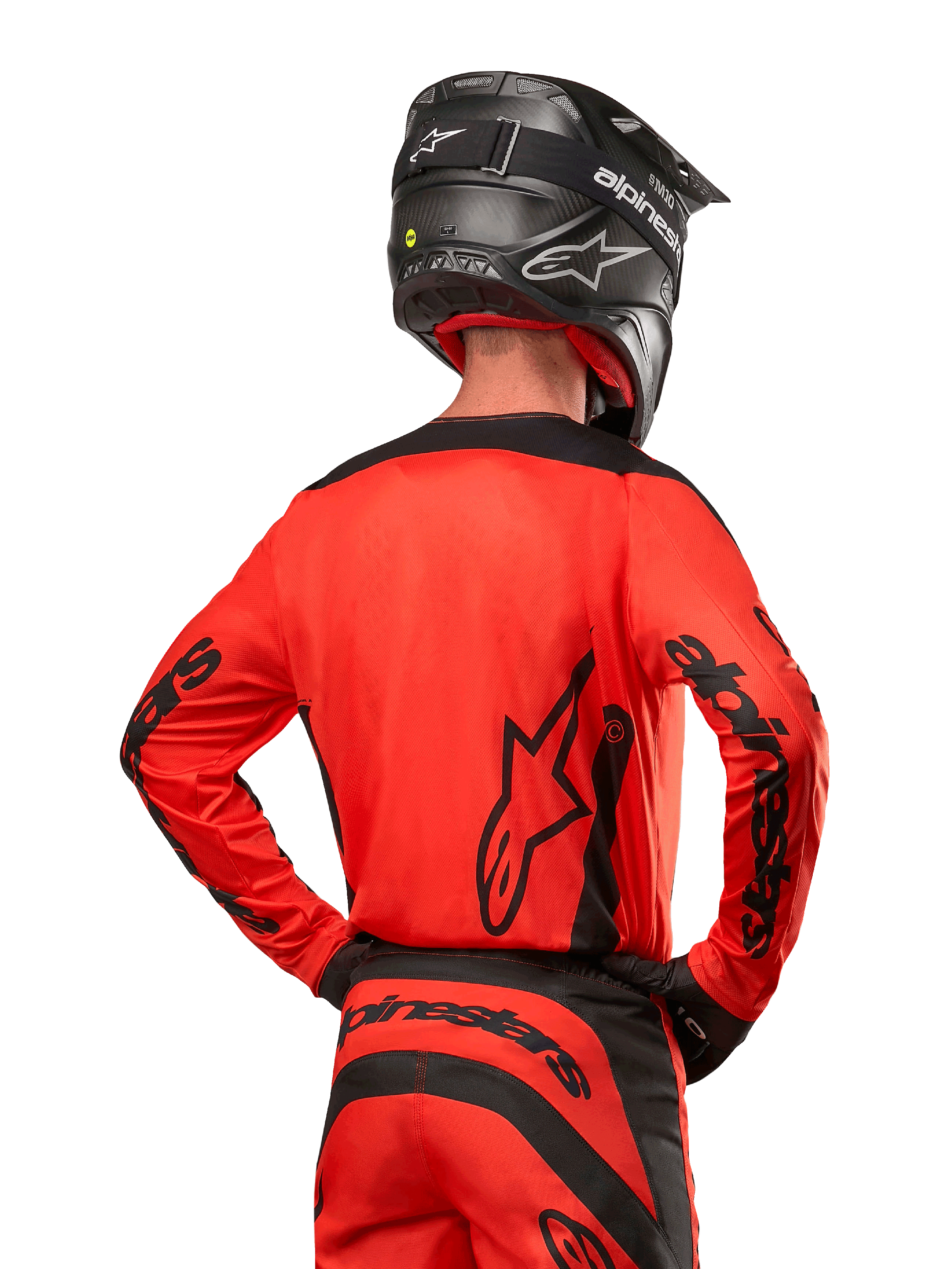 Motocyklista motocrossowy widoczny od tyłu w koszulce Alpinestars 2024 Fluid Lurv w kolorze jaskrawopomarańczowym i czarnym, z wyraźnym brandingiem Alpinestars na plecach i rękawach, w zestawie z dopasowanymi spodniami motocrossowymi i czarnym kaskiem, zaprojektowana do jazdy off-road.