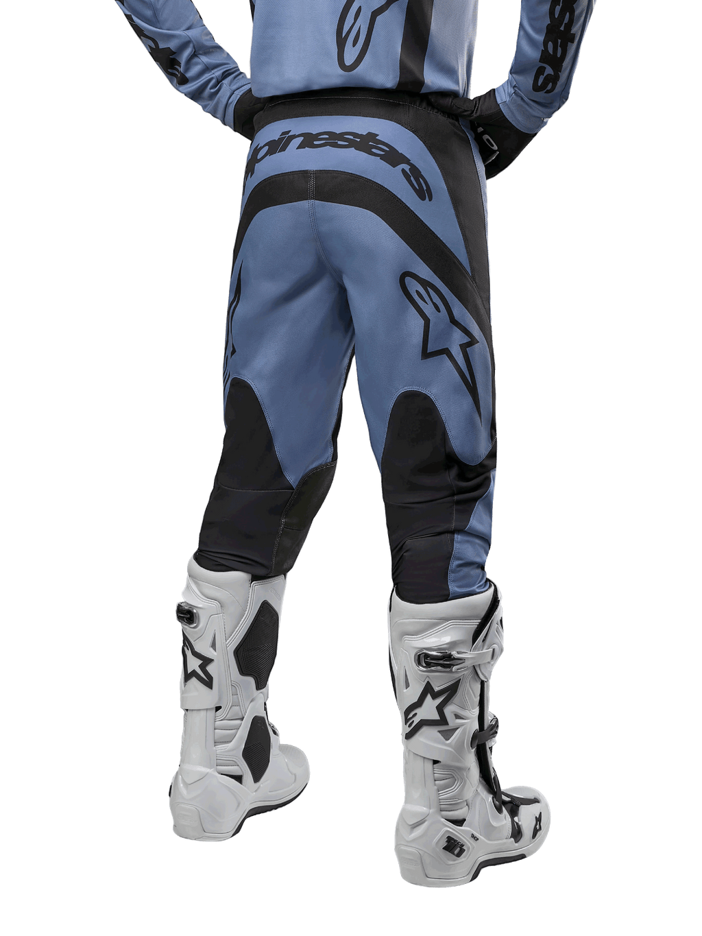 Alpinestars 2024 Fluid Lurv Pants, spodnie motocrossowe, jasnoniebieskie i czarne, widok z tyłu pokazujący czarne wzmocnione panele i duże logo marki, zestawione z biało-czarnymi butami motocrossowymi, profesjonalny sprzęt wyścigowy do jazdy terenowej