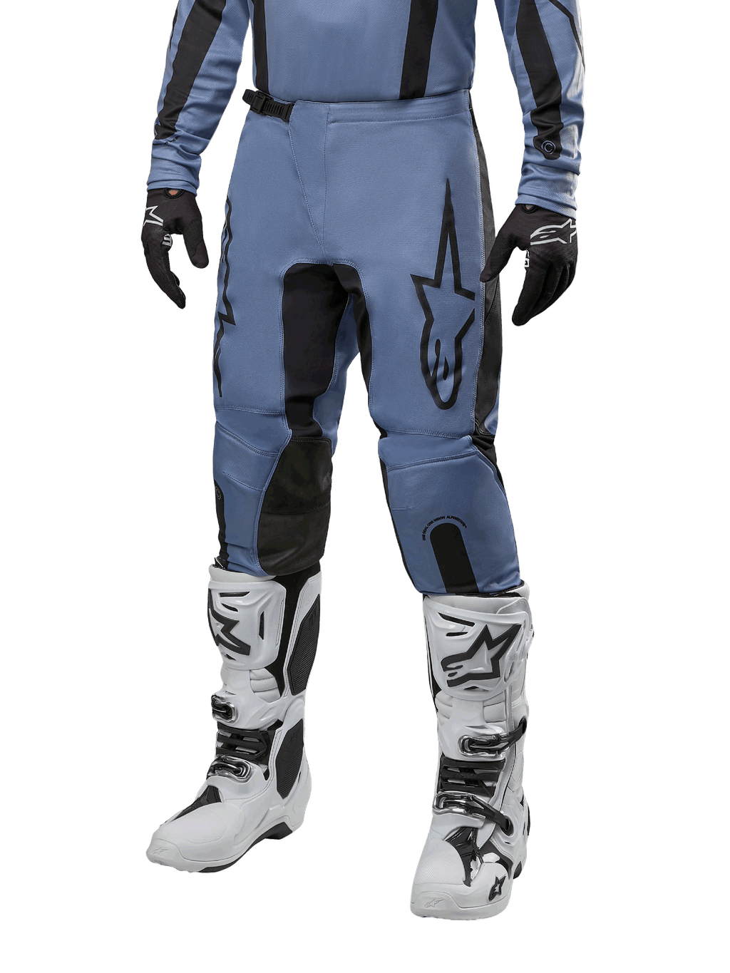 Spodnie Alpinestars Fluid Lurv 2024, spodnie motocrossowe, jasnoniebieskie i czarne, noszone z pasującą bluzą z długim rękawem i białymi butami motocrossowymi, z wyraźnym czarnym logo gwiazdy na udzie i wzmocnionymi panelami wewnętrznymi kolan, widok z przodu na białym tle