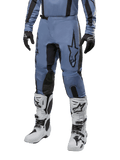 Spodnie Alpinestars Fluid Lurv 2024, spodnie motocrossowe, jasnoniebieskie i czarne, noszone z pasującą bluzą z długim rękawem i białymi butami motocrossowymi, z wyraźnym czarnym logo gwiazdy na udzie i wzmocnionymi panelami wewnętrznymi kolan, widok z przodu na białym tle