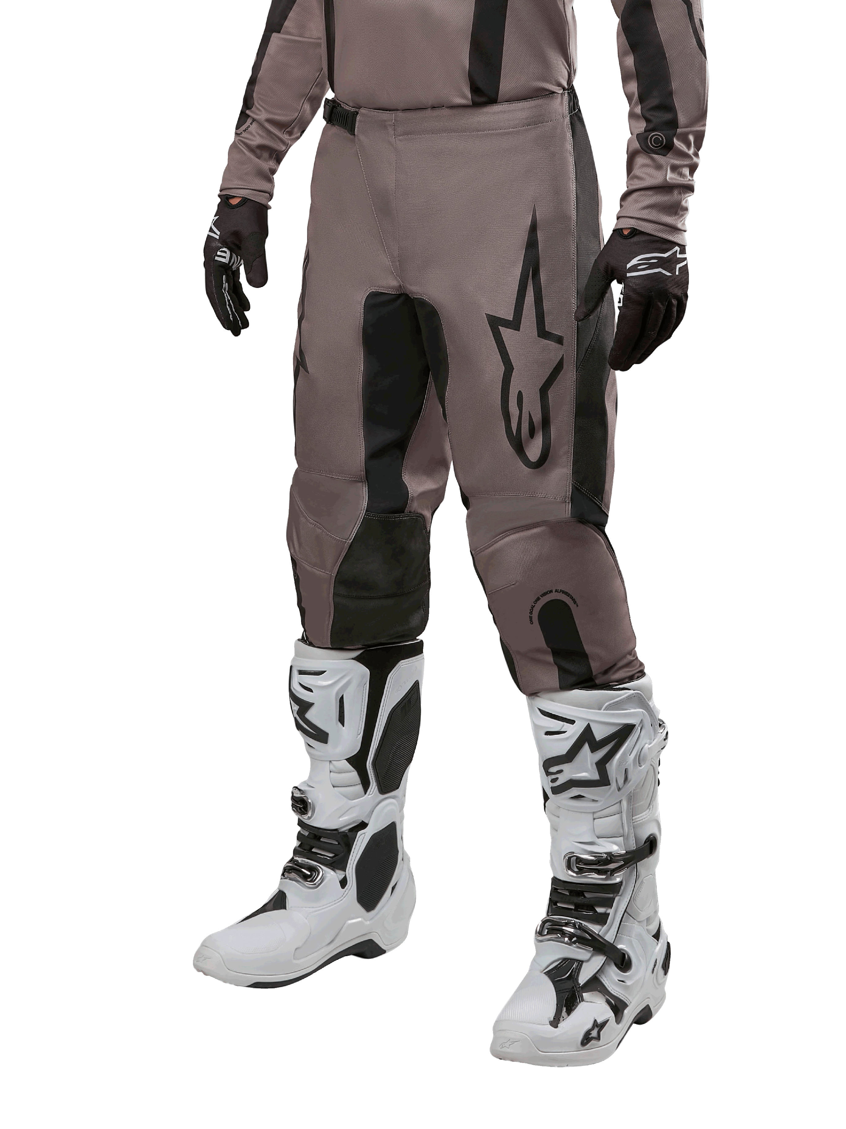 Alpinestars 2024 Fluid Lurv Pants, spodnie motocrossowe, kolor Mud Black i czarny, z logo Alpinestars, noszone z czarnymi rękawicami i białymi butami motocrossowymi, sportowy design do wyścigów terenowych