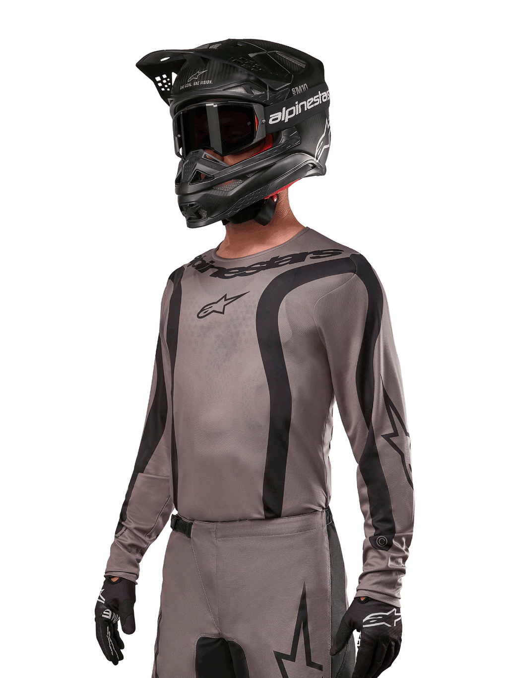 Alpinestars 2024 Fluid Lurv Jersey, koszulka motocrossowa w kolorze szarym i czarnym (Mud Black), model z długim rękawem, czarnymi zakrzywionymi pasami i logo, zestawiona z pasującymi spodniami i czarnym kaskiem motocrossowym, profesjonalny strój off-road