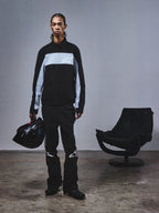 Alpinestars RSRV Track Jacket, czarna i szara bluza sportowa z logo gwiazdy, osoba trzymająca czarny kask, nowoczesny styl miejski, premium streetwear z dziedzictwem motorsportu