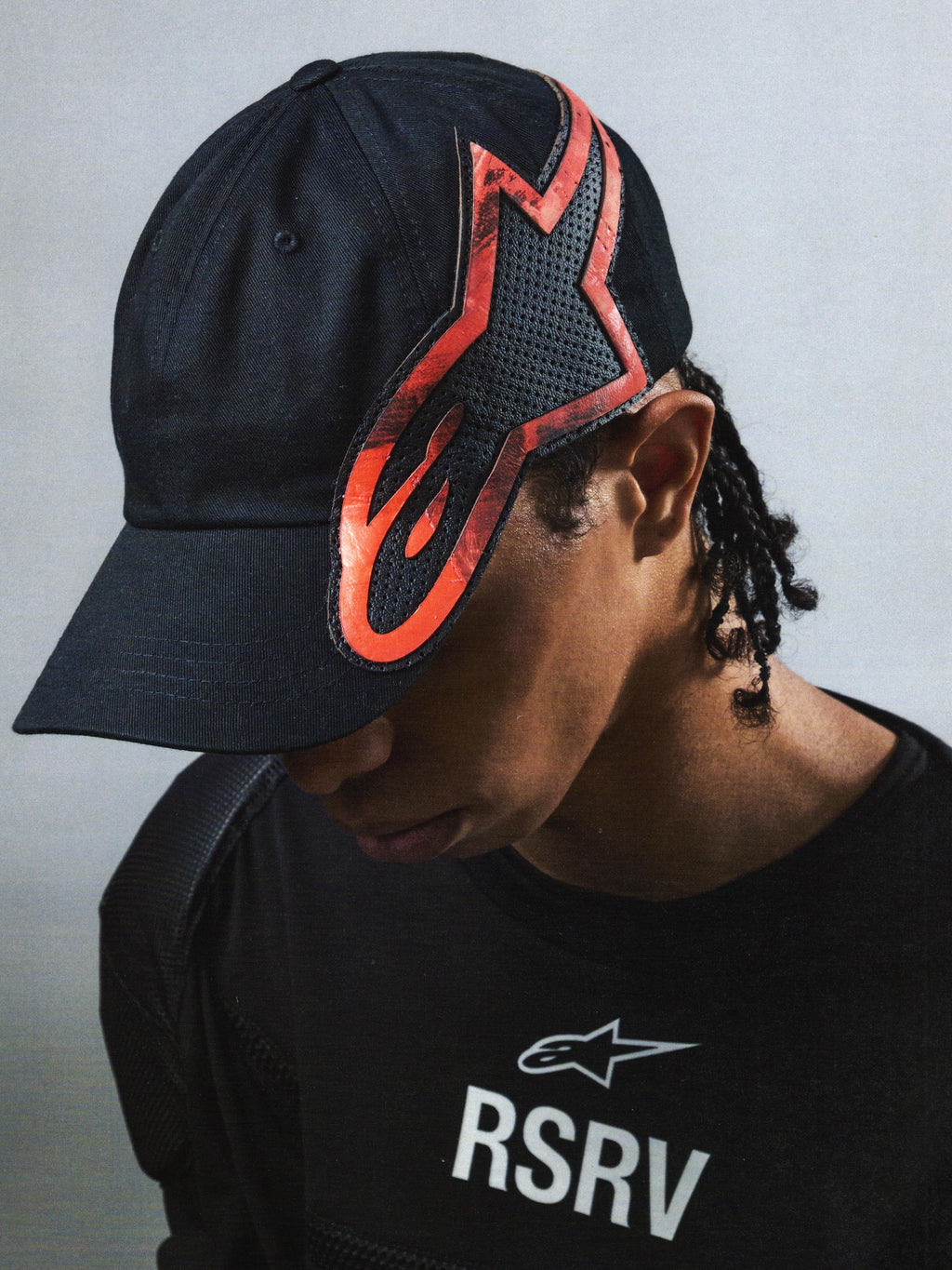 Alpinestars RSRV Lowside Hat, czarna czapka z czerwono-czarnym płomieniowym logo, unisex, gładka tekstura z perforacją, streetwear inspirowany motorsportem
