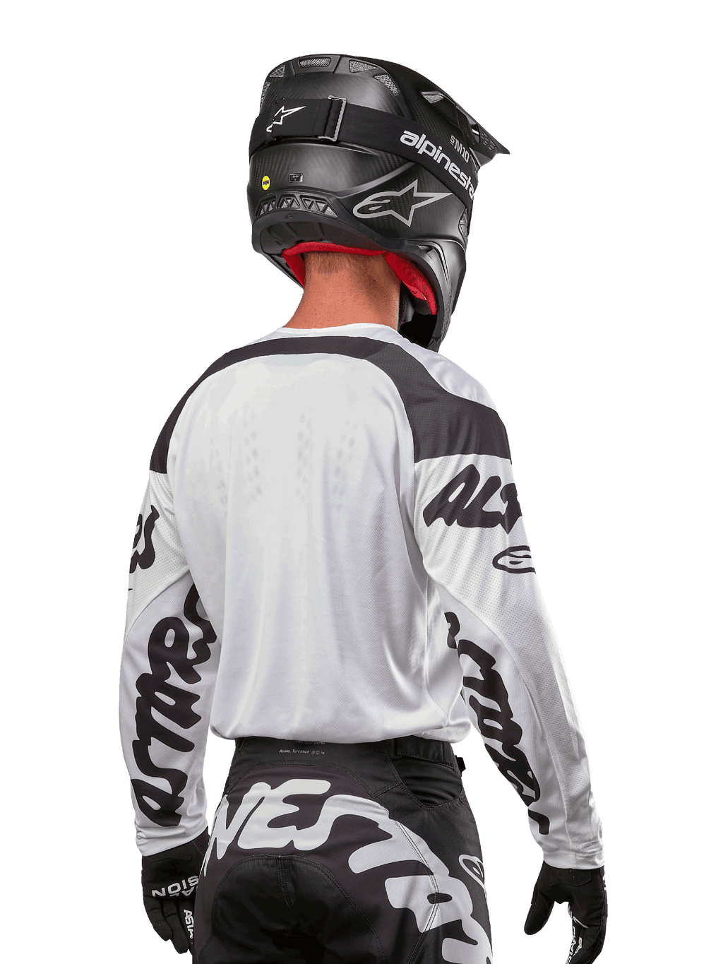 Koszulka Alpinestars Racer Hana 2024, biało-czarna, widok z tyłu prezentujący ergonomiczny krój i wyraźne logo na rękawach, zestawiona z czarnym kaskiem motocrossowym i pasującymi czarno-białymi spodniami, profesjonalny sprzęt wyścigowy do jazdy terenowej