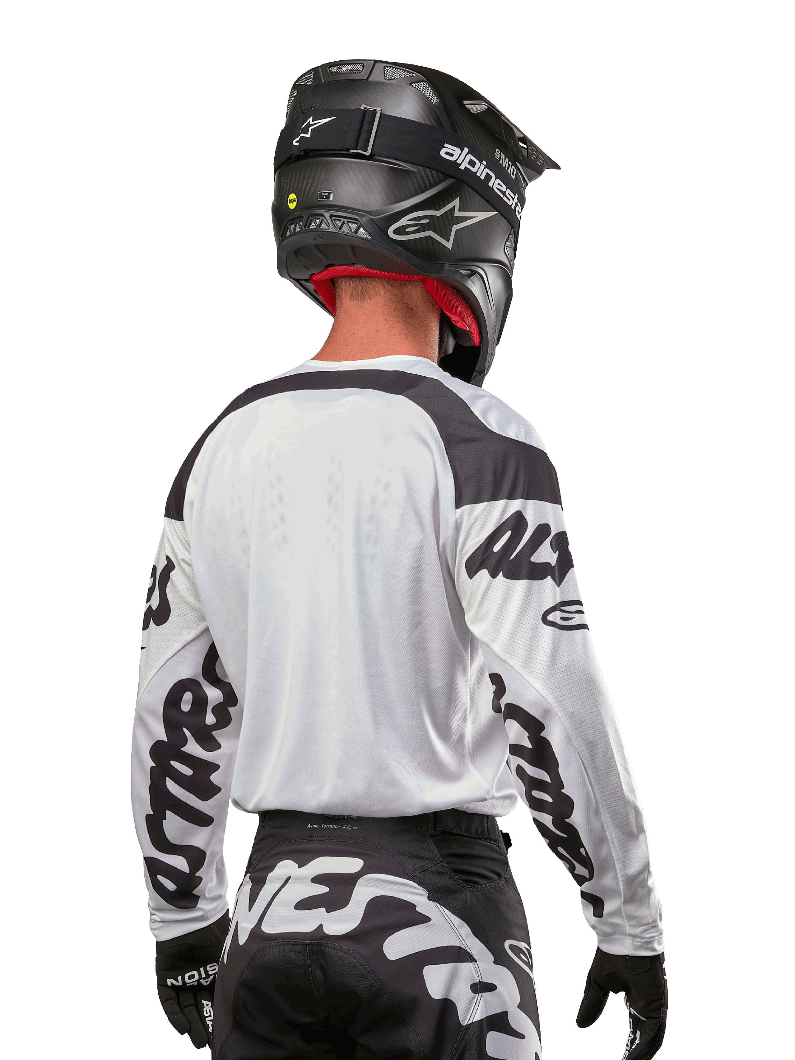 Koszulka Alpinestars Racer Hana 2024, biało-czarna, widok z tyłu prezentujący ergonomiczny krój i wyraźne logo na rękawach, zestawiona z czarnym kaskiem motocrossowym i pasującymi czarno-białymi spodniami, profesjonalny sprzęt wyścigowy do jazdy terenowej