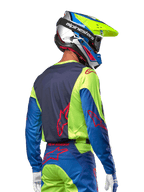 Motocyklista motocrossowy w koszulce Alpinestars 2024 Racer Hoen, kolor żółty fluo i granatowy (Blue Night Navy), z czerwonym logo gwiazdy na plecach, pasujące spodnie i kask wyścigowy, widok z tyłu prezentujący ergonomiczny design do jazdy terenowej.
