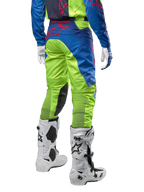 Alpinestars 2024 Racer Hoen Pants, spodnie motocrossowe, żółte fluo i granatowe, widok z tyłu, z czerwonym logo Alpinestars, zestawione z pasującą koszulką, białymi rękawicami i białymi butami motocrossowymi, wytrzymały materiał tekstylny do jazdy terenowej