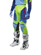 Alpinestars 2024 Racer Hoen Pants, spodnie motocrossowe, neonowożółte i granatowe, z czerwonymi logotypami gwiazdy i czarnymi panelami po wewnętrznej stronie kolan, zestawione z pasującą bluzą i białymi butami motocrossowymi, odzież wyczynowa do jazdy terenowej