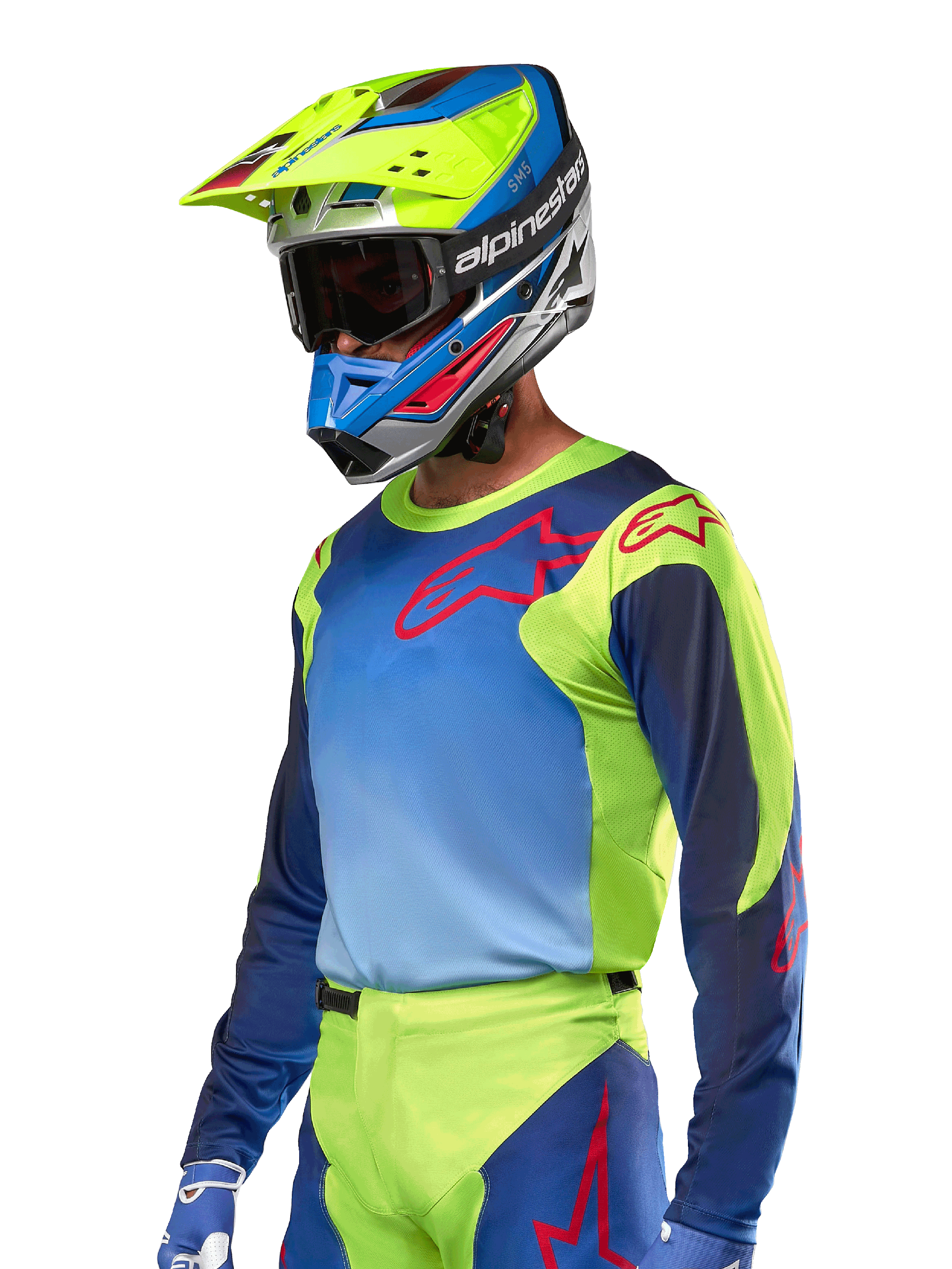 Koszulka Alpinestars Racer Hoen 2024, koszulka motocrossowa, kolory żółty fluo i granatowy z czerwonymi logotypami, noszona z pasującym żółto-niebiesko-czerwonym kaskiem i niebieskimi rękawicami, wyrazisty strój do jazdy terenowej