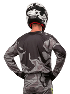 Alpinestars 2024 Racer Tactical Jersey, koszulka motocrossowa, Cast Gray Camo Magnet, widok z tyłu prezentujący szaro-czarny wzór kamuflażu, noszona z pasującymi spodniami i czarno-białym kaskiem, profesjonalna odzież do wyścigów terenowych