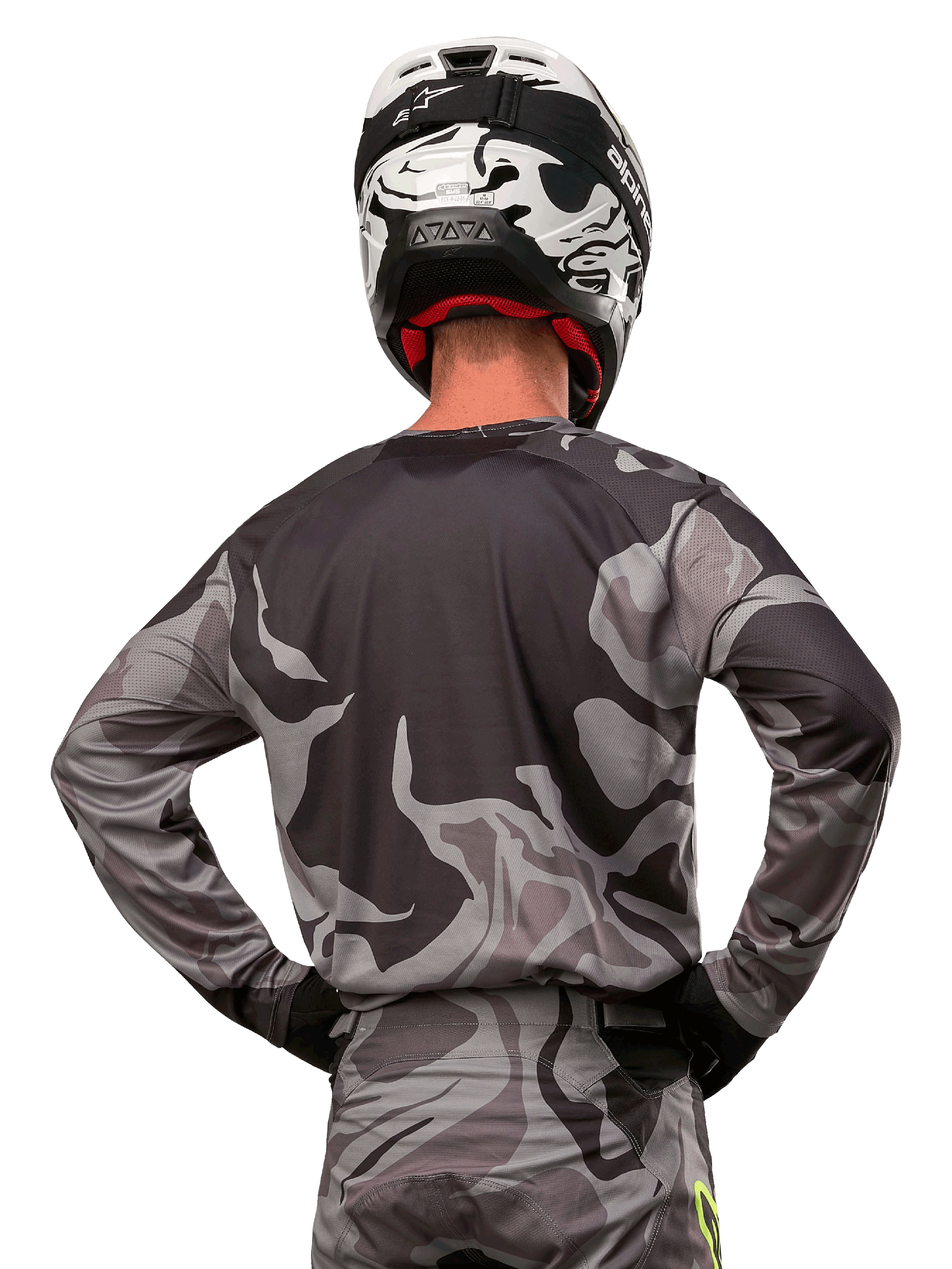 Alpinestars 2024 Racer Tactical Jersey, koszulka motocrossowa, Cast Gray Camo Magnet, widok z tyłu prezentujący szaro-czarny wzór kamuflażu, noszona z pasującymi spodniami i czarno-białym kaskiem, profesjonalna odzież do wyścigów terenowych
