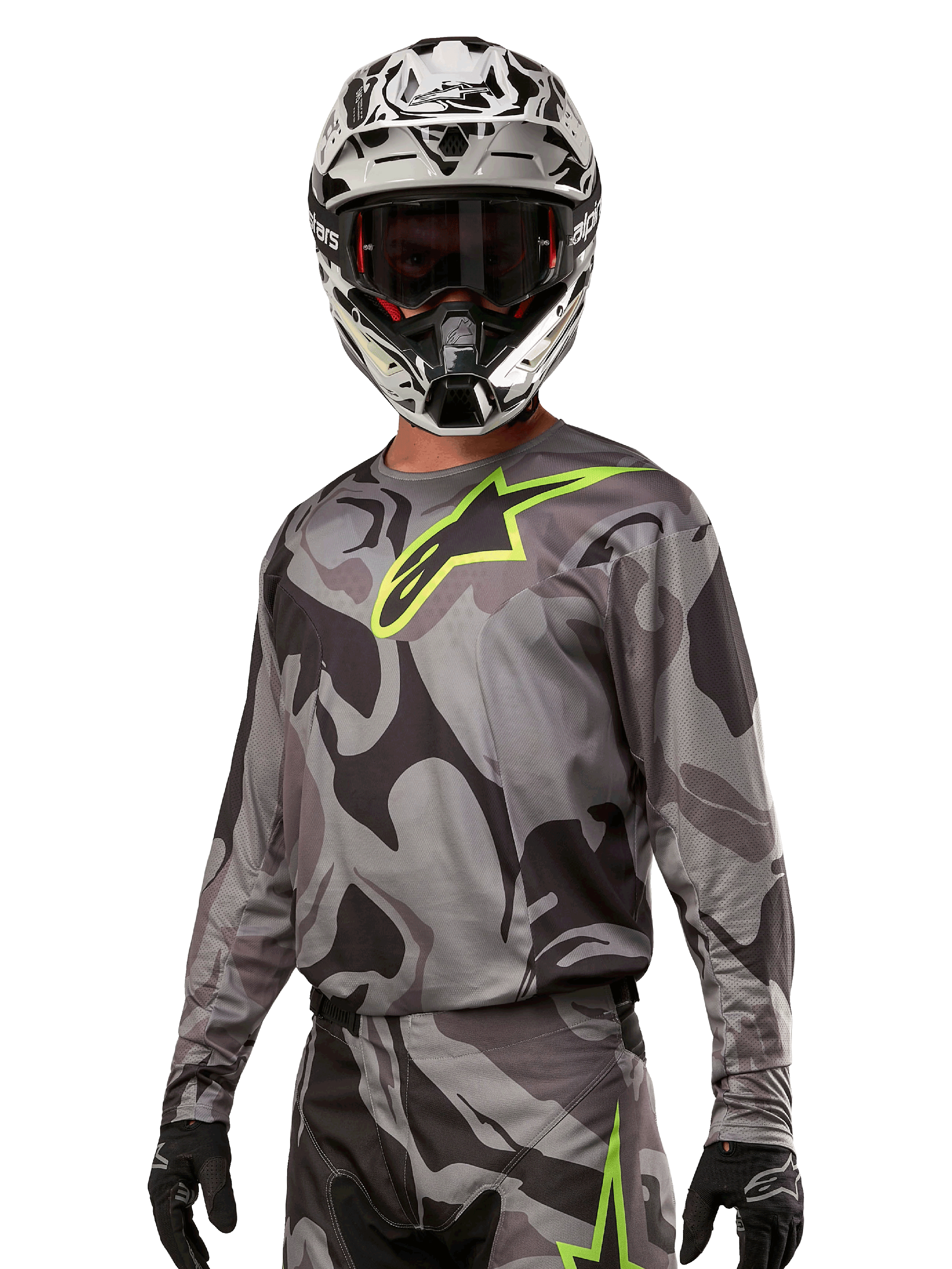 Alpinestars 2024 Racer Tactical Jersey, koszulka motocrossowa, szary kamuflaż Cast Gray Camo Magnet z neonowo zielonym logo, noszona z czarno-białym kaskiem i czarnymi rękawicami, techniczna tkanina odprowadzająca wilgoć do jazdy terenowej