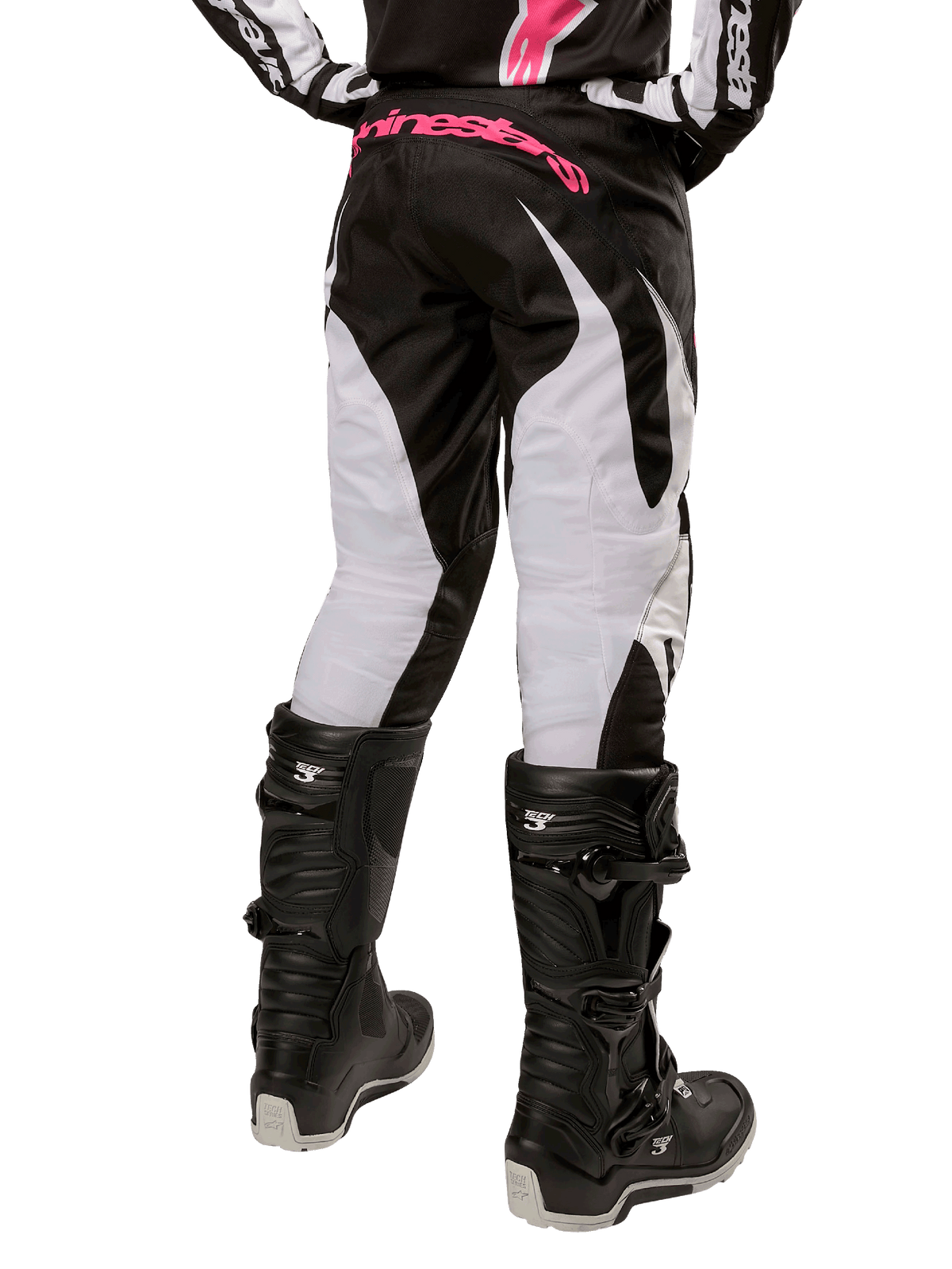 Alpinestars Stella Fluid 2024, damskie spodnie motocrossowe, czarno-białe, widok z tyłu ukazujący białe panele na nogawkach i różowe logo na pasie, noszone z czarnymi butami Tech 3, wytrzymały sprzęt do wyścigów terenowych