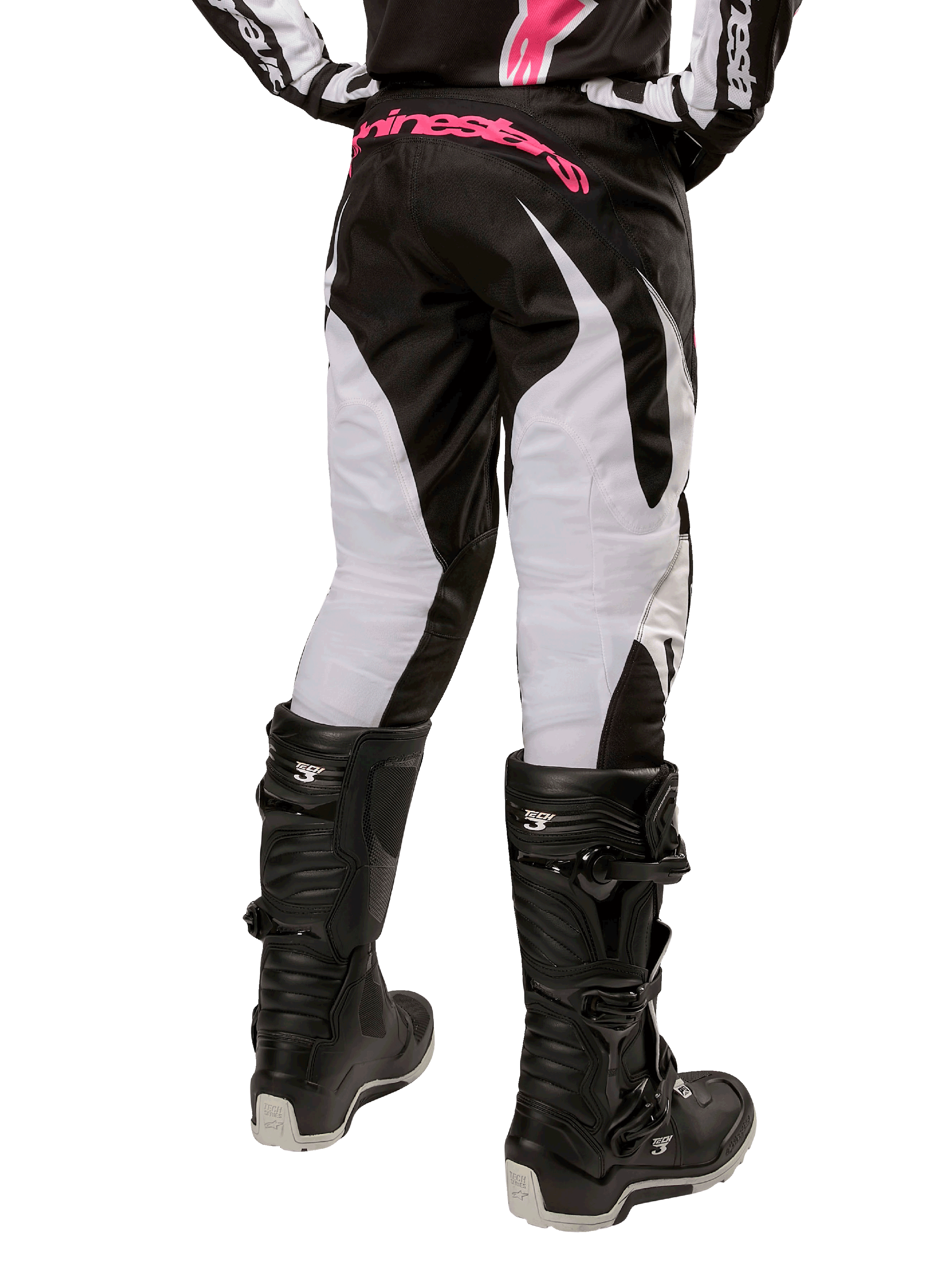 Alpinestars Stella Fluid 2024, damskie spodnie motocrossowe, czarno-białe, widok z tyłu ukazujący białe panele na nogawkach i różowe logo na pasie, noszone z czarnymi butami Tech 3, wytrzymały sprzęt do wyścigów terenowych