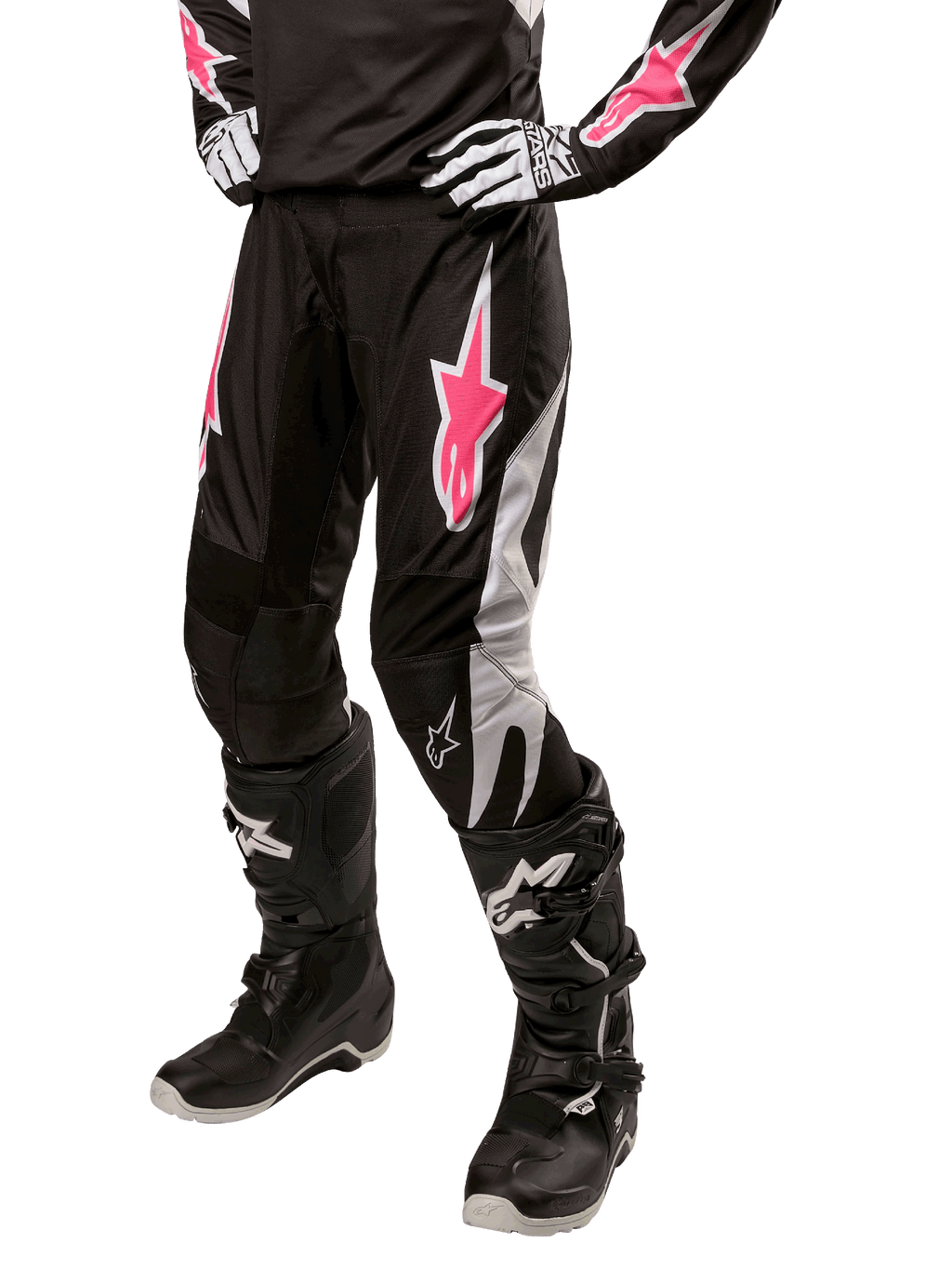 Damskie spodnie Alpinestars Stella Fluid 2024, spodnie motocrossowe, czarno-białe z różowymi akcentami, noszone z dopasowanym sprzętem ochronnym, w tym butami i rękawicami, wytrzymały elastyczny materiał do jazdy terenowej