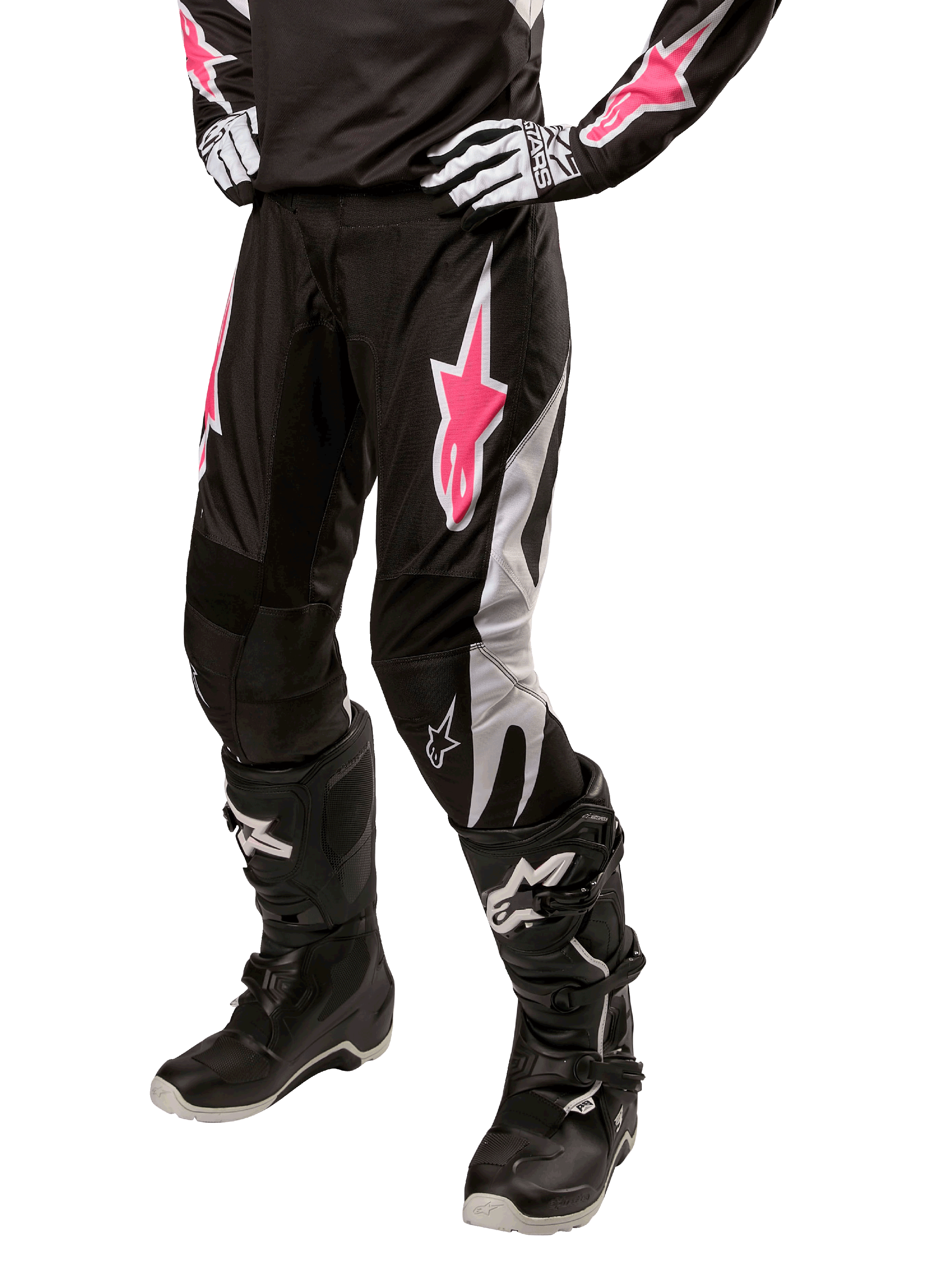 Damskie spodnie Alpinestars Stella Fluid 2024, spodnie motocrossowe, czarno-białe z różowymi akcentami, noszone z dopasowanym sprzętem ochronnym, w tym butami i rękawicami, wytrzymały elastyczny materiał do jazdy terenowej