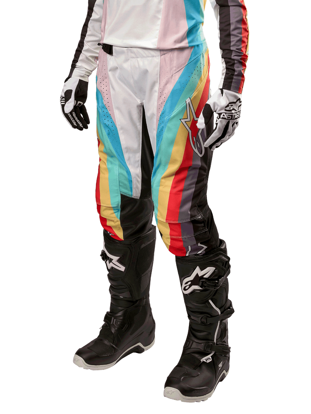 Alpinestars Stella Techstar 2024, damskie spodnie motocrossowe, czarne wielokolorowe z ukośnymi czerwonymi, żółtymi i niebieskimi pasami, widoczne z czarnymi butami i białymi rękawicami, z czarnymi panelami ochronnymi na kolanach i wyrazistym logo do wyścigów off-road