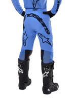Alpinestars Supertech Dade Pants 2024, spodnie motocrossowe, jasnoniebieskie, widok z tyłu z dużym czarnym brandingiem na siedzeniu i nogawkach, noszone z czarnymi butami Alpinestars Tech 10, sportowy krój wyścigowy zapewniający profesjonalne osiągi w terenie