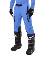Alpinestars Supertech Dade Pants 2024, spodnie motocrossowe, jasnoniebieskie z czarnymi grafikami logo, perforacje wentylacyjne, magnetyczna klamra w pasie, czarne techniczne buty i rękawice, profesjonalna odzież do wyścigów off-road