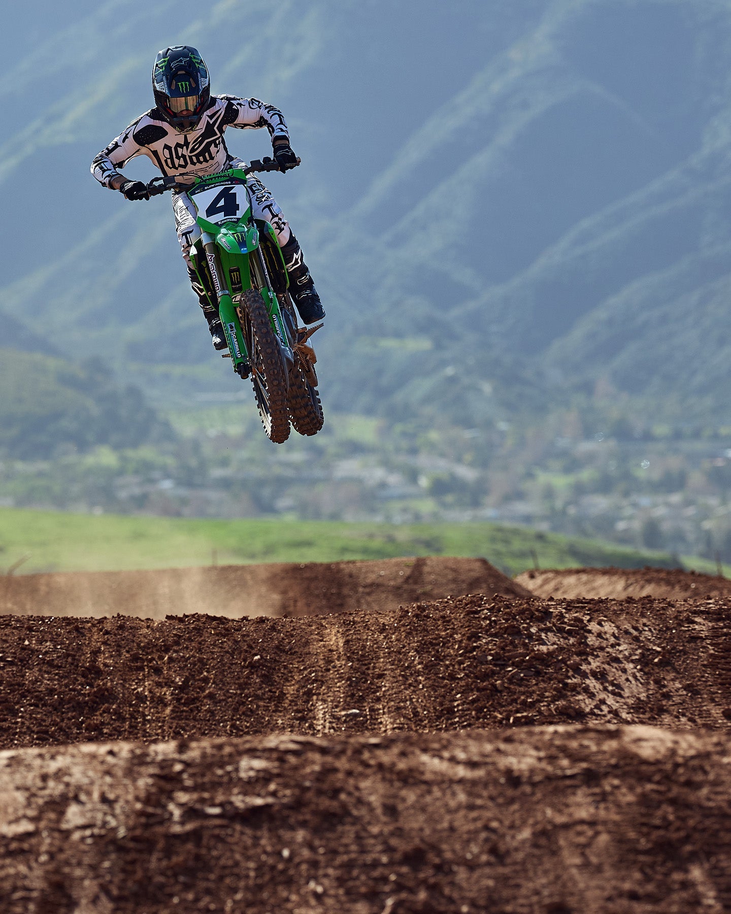Alpinestars Limited Edition S-M7 Wolf Dust Helmet and Visor, black and white motocross gear, jumping a green bike.