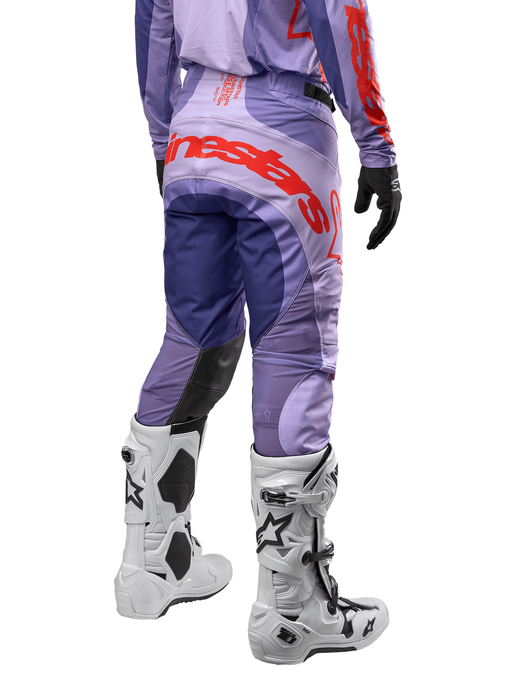 Alpinestars Techstar Ocuri Pants 2024, spodnie motocrossowe, fioletowe z intensywnymi pomarańczowymi i ciemnoniebieskimi akcentami, duże pomarańczowe logo Alpinestars z tyłu, białe buty motocyklowe, sportowy krój wyścigowy