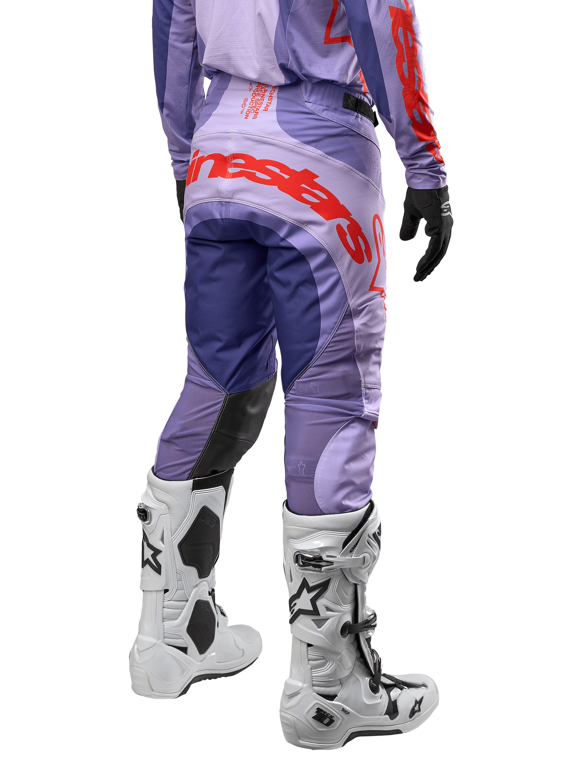Alpinestars Techstar Ocuri Pants 2024, spodnie motocrossowe, fioletowe z intensywnymi pomarańczowymi i ciemnoniebieskimi akcentami, duże pomarańczowe logo Alpinestars z tyłu, białe buty motocyklowe, sportowy krój wyścigowy