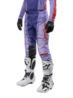 Alpinestars Techstar Ocuri Pants 2024, spodnie motocrossowe, fioletowe z jaskrawopomarańczowymi detalami, czerwone logo, białe buty motocrossowe i czarne rękawice, sportowy design off-road