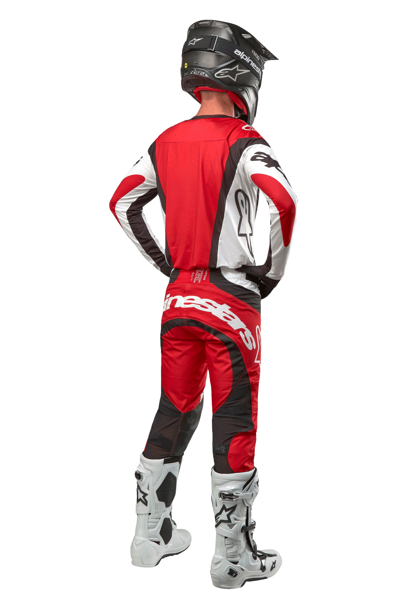 Alpinestars 2024 Techstar Ocuri Pants, spodnie motocrossowe, kolor Mars Red White Black, widok z tyłu na zawodnika motocrossowego w pełnym stroju wyścigowym, w tym pasującą bluzę, czarny kask oraz biało-czarne buty, podkreślający branding Alpinestars i trwałą konstrukcję materiału.