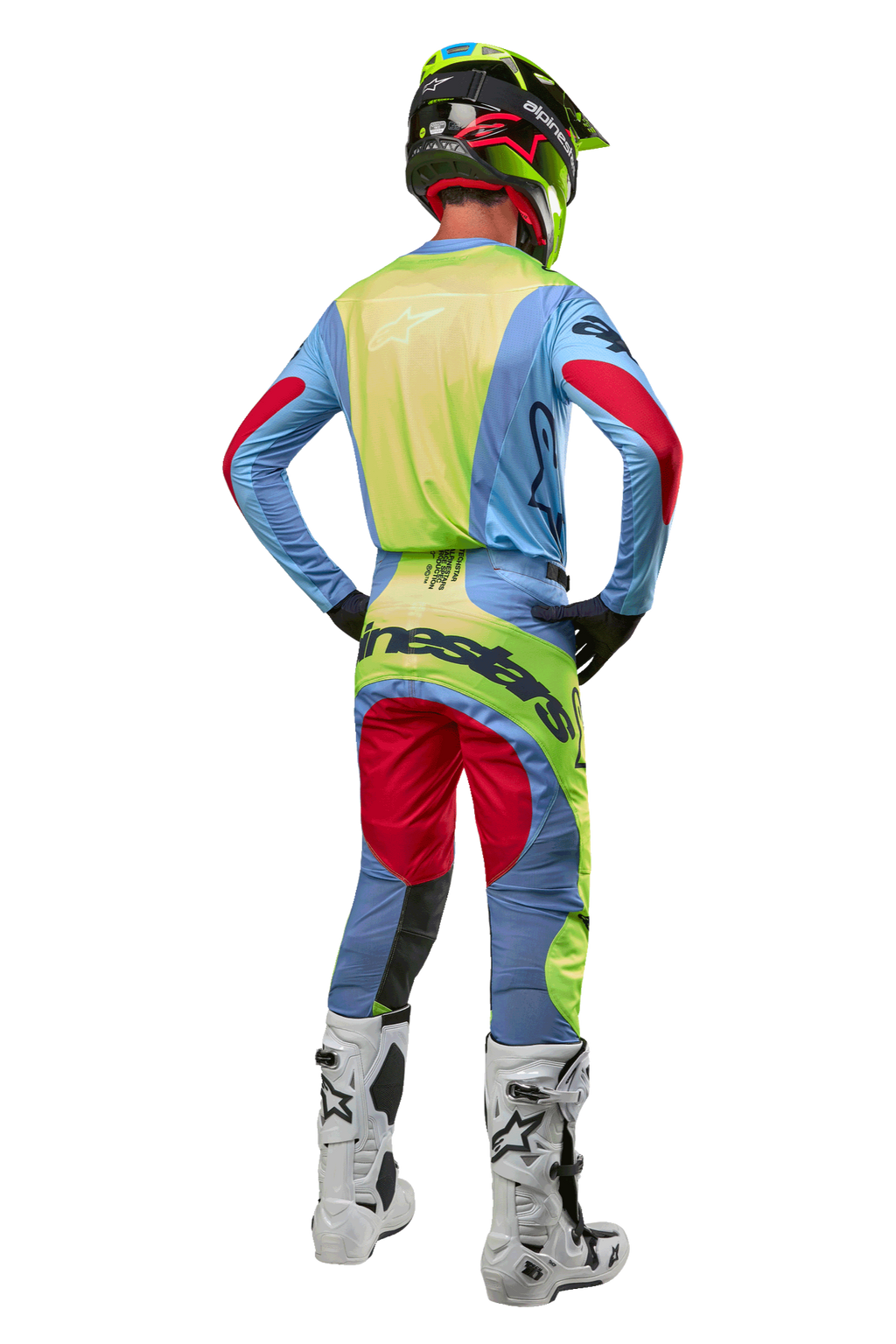 Kierowca motocrossowy widoczny od tyłu w spodniach i pasującej koszulce Techstar Ocuri 2024, kolory jasnoniebieski, neonowy żółty i czerwony Red Berry, biało-czarne buty, czarny kask z neonowymi akcentami, dopasowany strój Alpinestars do wyścigów off-road