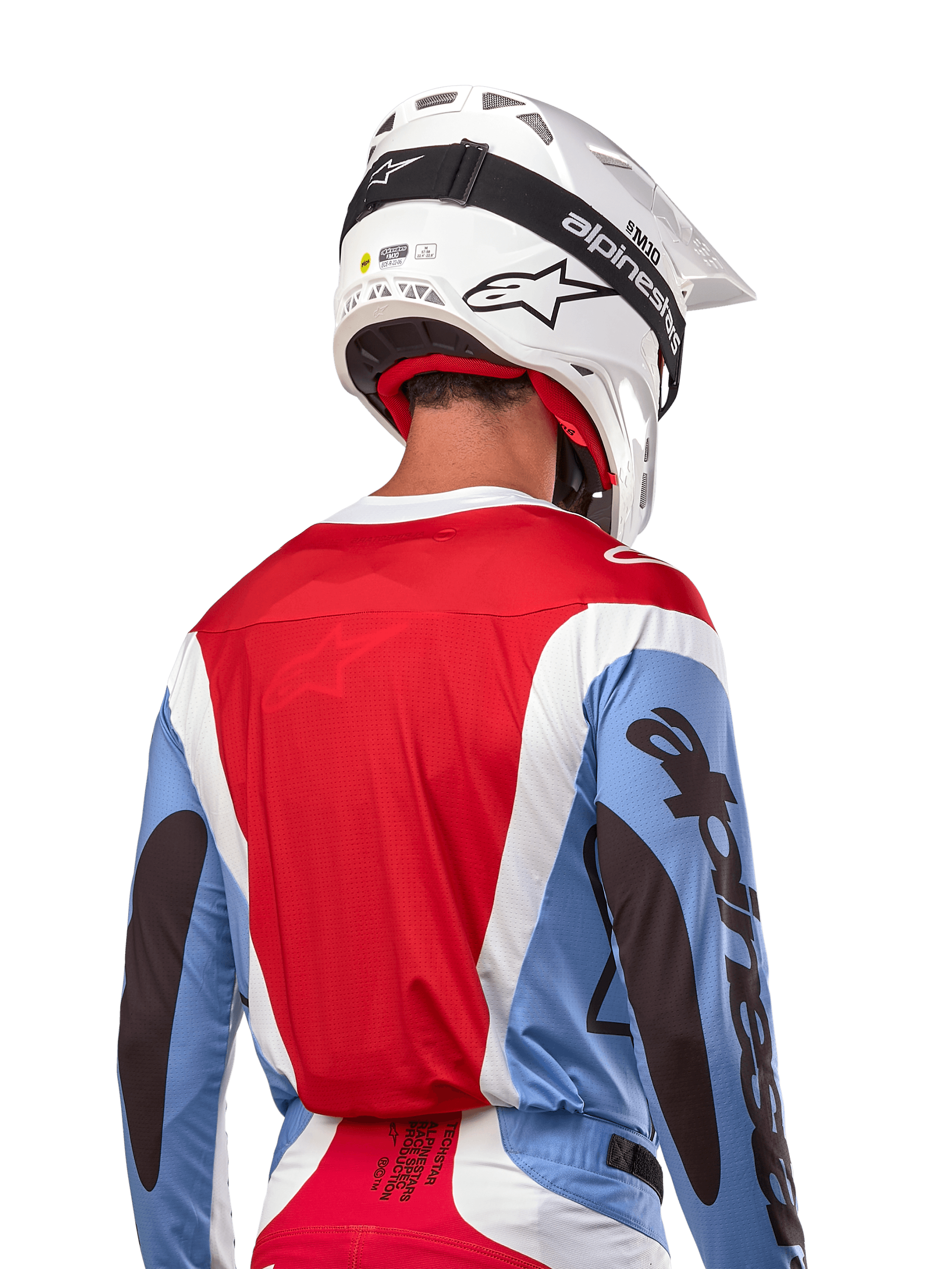 Alpinestars 2024 Techstar Ocuri Jersey, koszulka motocrossowa, jasnoniebieska, czerwona Mars Red i biała, widok z tyłu na motocyklistę w pasującym białym kasku i czarnych goglach, wyraźne czarne logo na rękawach, ergonomiczny krój wyścigowy dla wydajności off-road