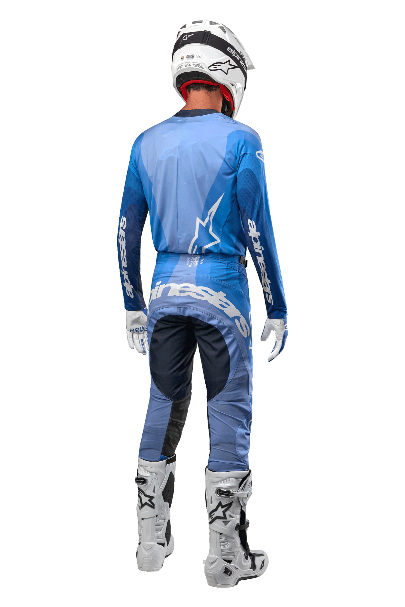 Motocyklista motocrossowy widziany od tyłu, ubrany w spodnie Alpinestars 2024 Techstar Pneuma w kolorze ciemnogranatowym i jasnoniebieskim, zestawione z pasującą niebieską koszulką, białym kaskiem, białymi rękawicami i białymi butami, z wyraźnym brandingiem Alpinestars na siedzeniu i rękawach.