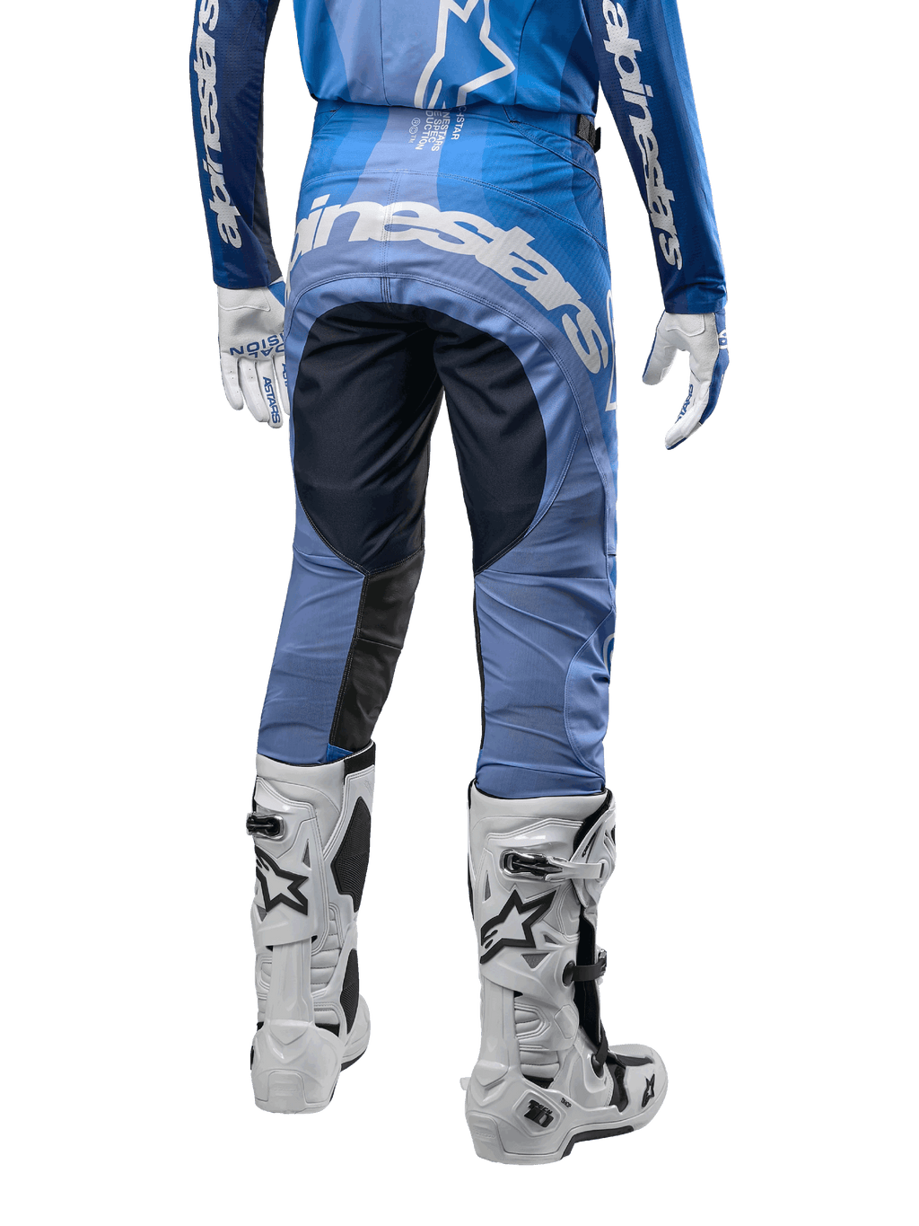 Alpinestars Techstar Pneuma Pants 2024, spodnie motocrossowe, ciemnogranatowe i jasnoniebieskie, widok z tyłu z wyraźnym białym logo na siedzeniu i wzmocnionymi czarnymi panelami, zestawione z białymi butami motocrossowymi Tech 10